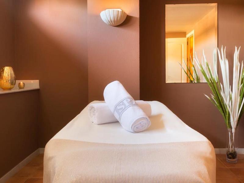 Gezellige wellnessruimte met massagetafel, kaarsen en decoratieve planten voor ontspanning.