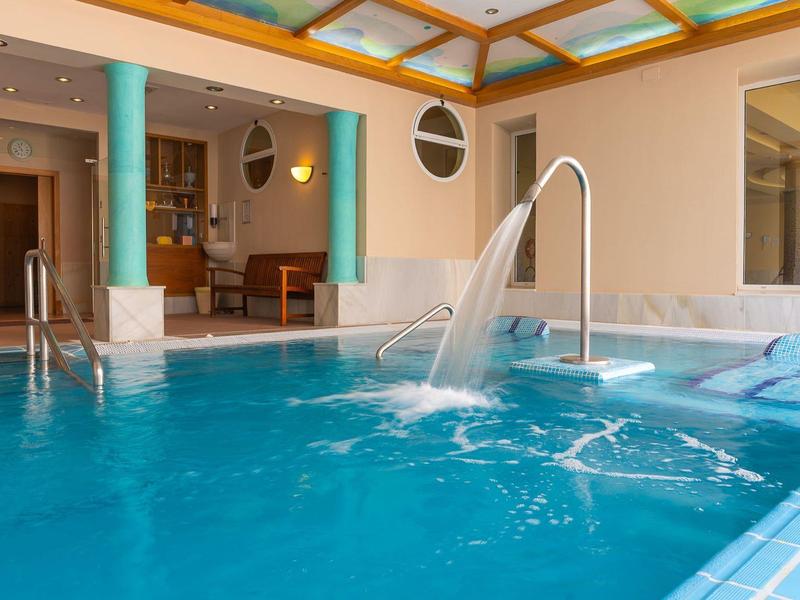 Binnenruimte met verwarmd zwembad, waterfontein en ontspannende whirlpools in hotelomgeving.
