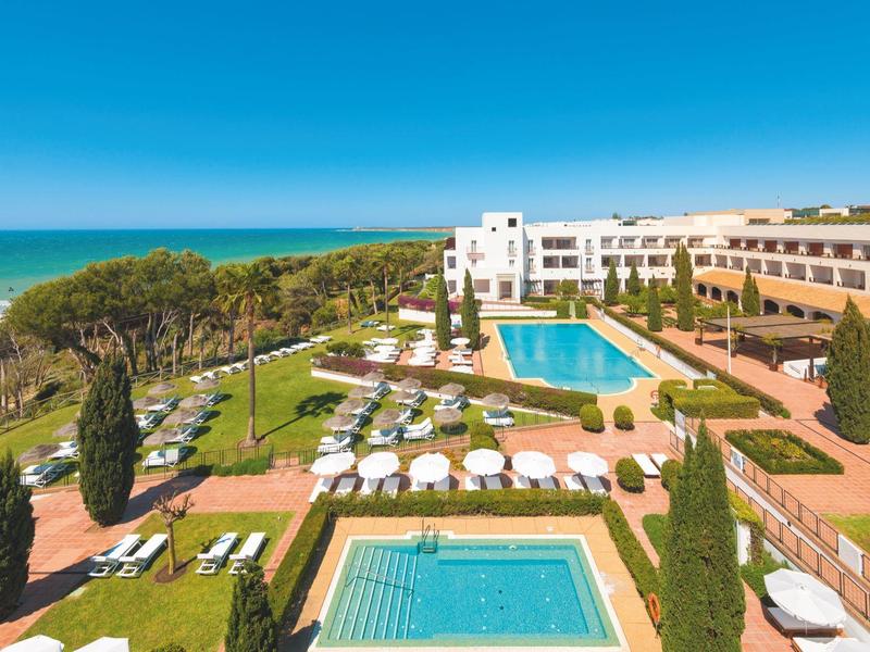 Moderne binnenruimte met rieten stoelen en uitzicht op een zonnig buitenterras van een hotel.