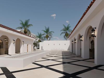 Cortile di un hotel con pareti bianche, archi e palme sotto un cielo azzurro.