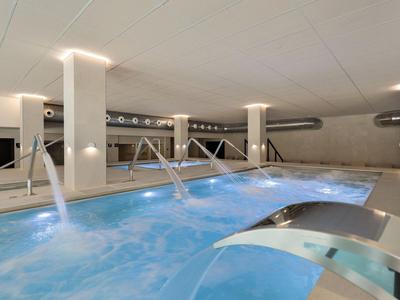 Nowoczesny basen wewnętrzny z dyszami wodnymi i relaksującą atmosferą w hotelu.