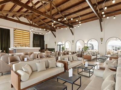Przestronny, jasny salon hotelowy z drewnianymi belkami stropowymi i wygodnymi sofami.