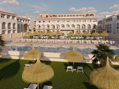 Hotel di lusso con grande piscina, lettini e ombrelloni di paglia in un ambiente tropicale.