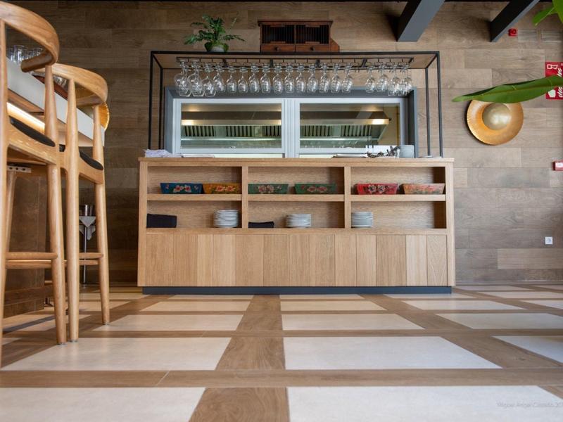 Houten stoelen en een buffetkast met planken in een moderne eetkamer met betegelde vloer.