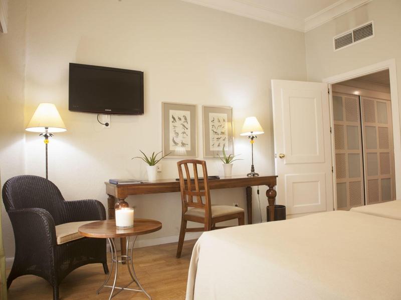 Gezellige hotelkamer met bed, bureau, fauteuil, lampen en wand-tv.