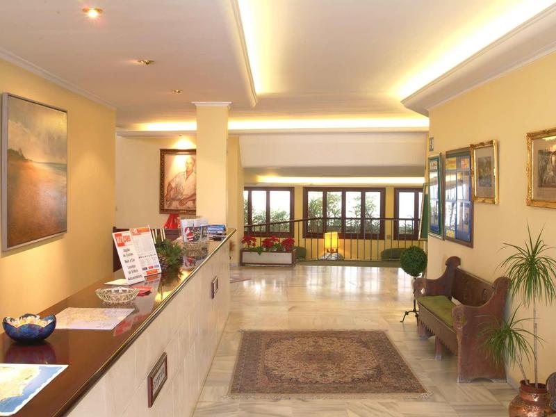 Luminosa hall dell'hotel con banco reception, area salotto e finestre dal pavimento al soffitto.