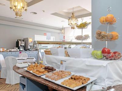 Bright hotel lounge with cupcakes, cookies, and chandeliers, ready for guests.