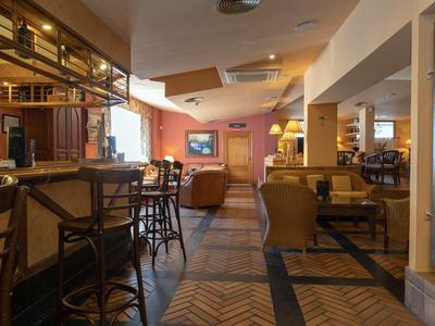 Warm, cozy hotel lounge with wooden floors and varied seating arrangements under soft lighting.