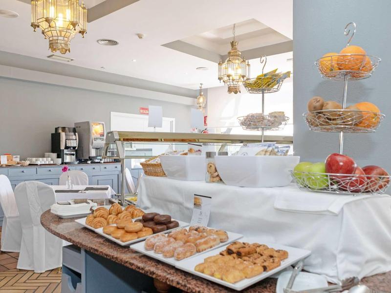 Bright hotel lounge with cupcakes, cookies, and chandeliers, ready for guests.