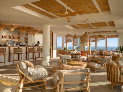 Otevřená lounge s dřevěným nábytkem a výhledem na moře v světlém hotelu