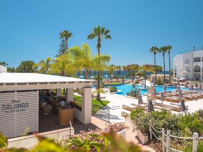 Moderní bazénová oblast s deštníky a lehátky vedle baru v hotelu.