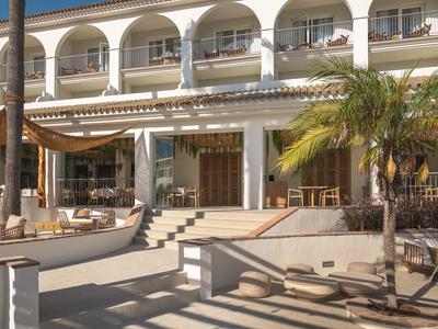 Vnější pohled na vícepatrový hotel s balkony a palmami v popředí