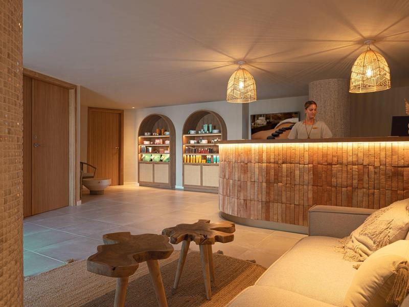 Pohodlný hotelový salónek s ambientním osvětlením, dřevěným nábytkem a recepcí.