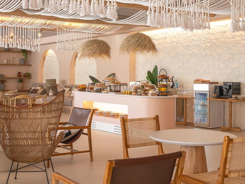 Světlé moderní café s bambusovými židlemi a pultem s rostlinami v pozadí