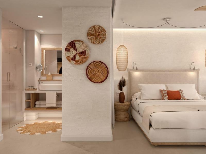 Moderní hotelový pokoj s béžovými tóny, pohodlnou postelí, dekorativními koši na stěně a viditelnou koupelnou.