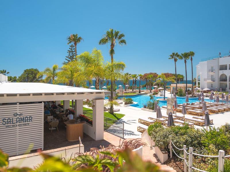 Moderní bazénová oblast s deštníky a lehátky vedle baru v hotelu.