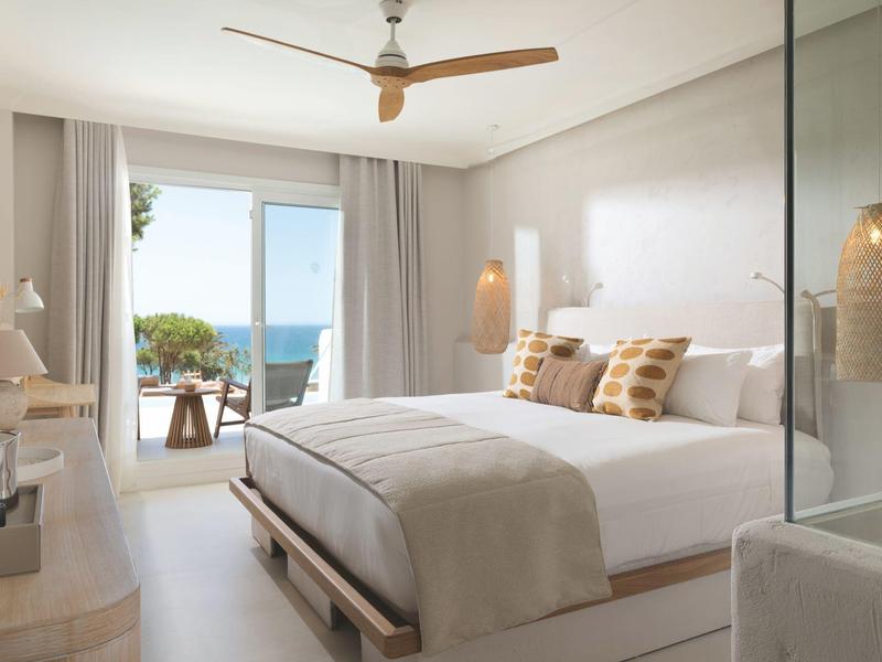 Světý moderní hotelový pokoj s velkou postelí, balkonem s výhledem na moře a neutrálním zařízením.
