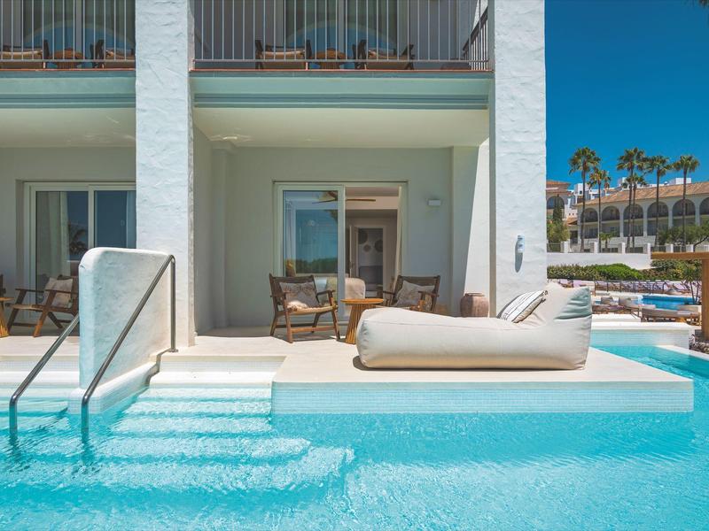 Venkovní bazén s lehátkem a patio dveřmi vedoucími do hotelových pokojů.