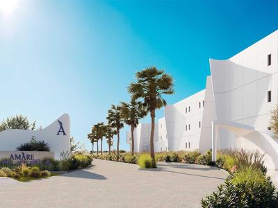 Moderní bílý hotelový komplex s palmami a modrou oblohou v pozadí.