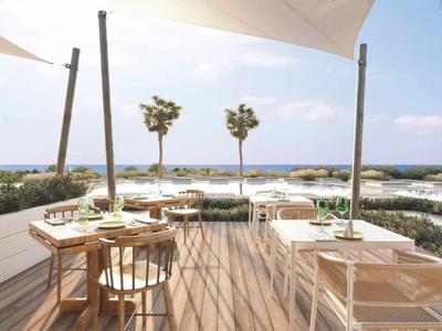 Terrasse mit Holzboden, Tisch und Stühlen mit Blick auf das Meer und Palmen.