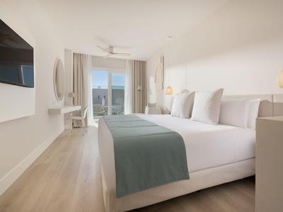 Modernes Hotelzimmer mit großem Bett, Holzfußboden und Zugang zu Balkon mit Aussicht.