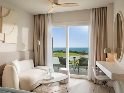 Modern eingerichtetes Hotelzimmer mit Meerblick und Terrasse bei natürlichem Tageslicht.