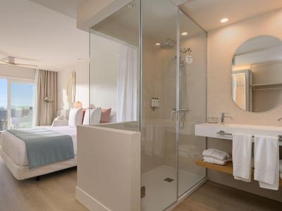 Modern eingerichtetes Hotelzimmer mit Doppelbett und separater Dusche in Glas.