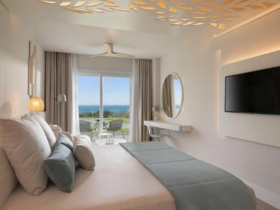 Minimalistisches Hotelzimmer mit Doppelbett, Meerblick und modernem Interieur in hellen Farben.