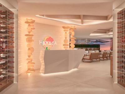 Moderní hotelová recepce s bílým pultem, osvětlenými sloupy a posezením v pozadí.