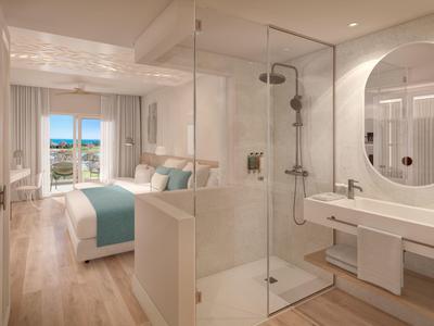 Moderní hotelový pokoj s manželskou postelí a otevřeným sprchovým koutem se skleněnou přepážkou s výhledem na město.