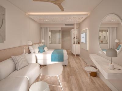 Moderně zařízený hotelový pokoj s postelí, pohovkou a jednoduchou výzdobou v světlých barvách.