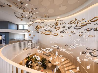 Elegante Hotellobby mit geschwungener Treppe und moderner, schwebender Dekoration an der Decke.