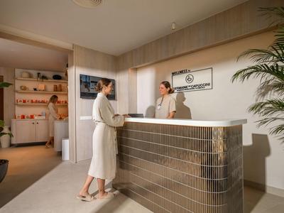 Rezeption in einem modernen Hotel mit zwei Personen im Gespräch, ruhige und helle Atmosphäre.
