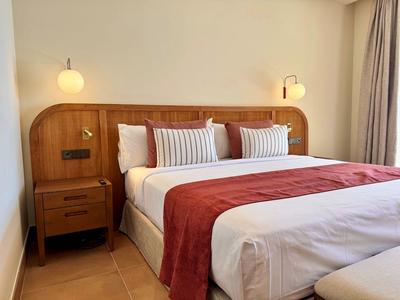 Modernes Hotelzimmer mit großem Bett, Holzkopfteil und roten Akzenten