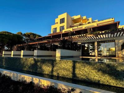 Modernes Hotelgebäude mit Terrasse und Glasfassade bei Sonnenuntergang.