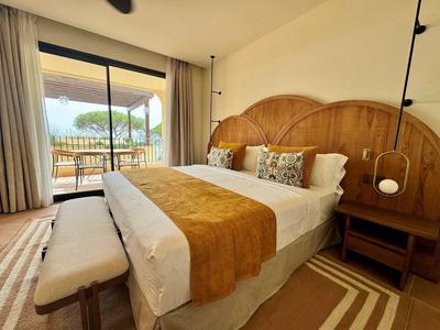 Gemütliches Hotelzimmer mit Doppelbett, Holzmöbeln und Balkon mit Blick auf Natur.