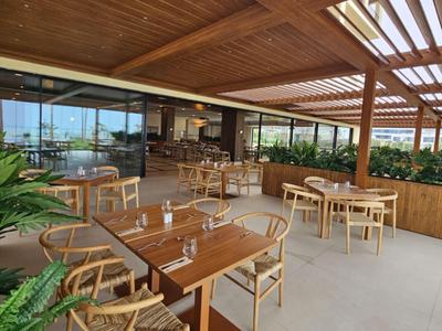 Überdachte Hotelterrasse mit Holzmöbeln und Pflanzen für entspannte Mahlzeiten im Freien.