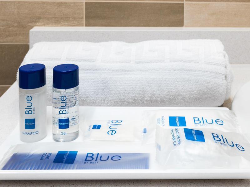 Vassoio con articoli da toeletta e asciugamani bianchi su un piano del bagno.