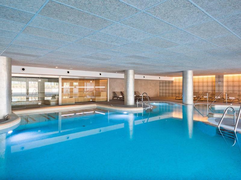 Piscina interna in un hotel moderno con acqua blu e pilastri.