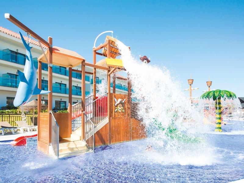 Parco acquatico con secchio rovesciato e scivoli nell'area piscina dell'hotel in una giornata di sole.