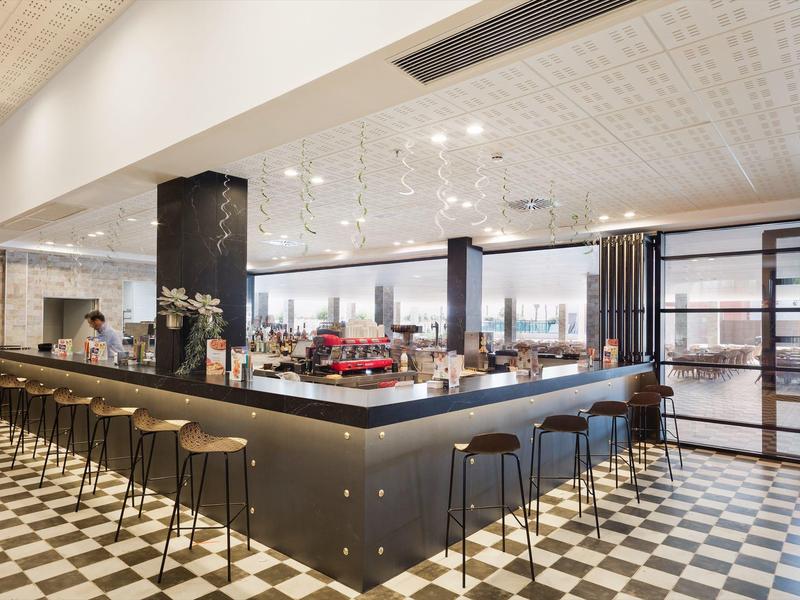 Interno moderno di un ristorante con un grande bar e pavimento a piastrelle bianco e nero.