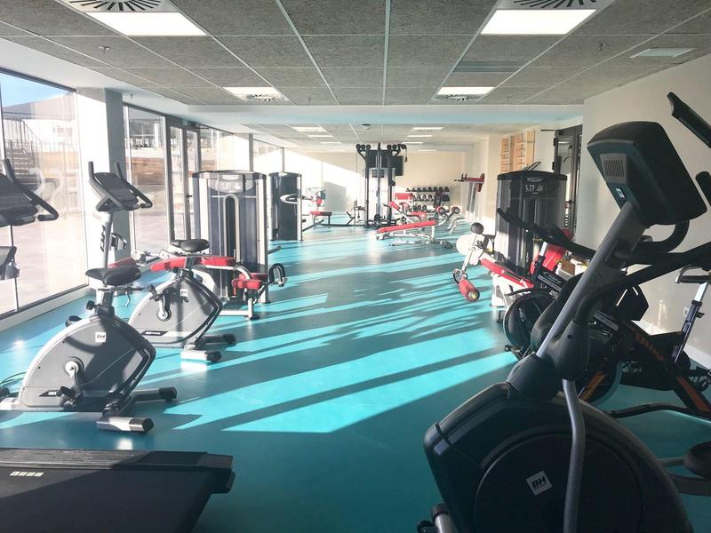 Palestra luminosa con cyclette e macchine per pesi in un hotel moderno.