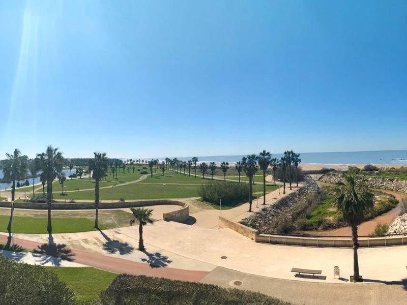 Campo da golf costiero con palme e cielo azzurro vicino alla spiaggia.