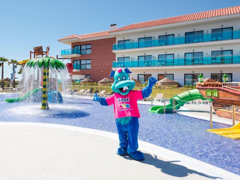 Mascotte con costume blu vicino a scivoli d'acqua e fontane nell'area piscina dell'hotel per famiglie.