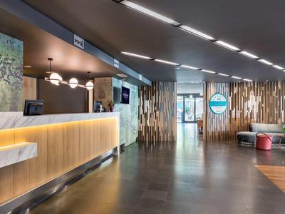 Moderna recepción de hotel con mostrador iluminado y paneles de madera en la pared.