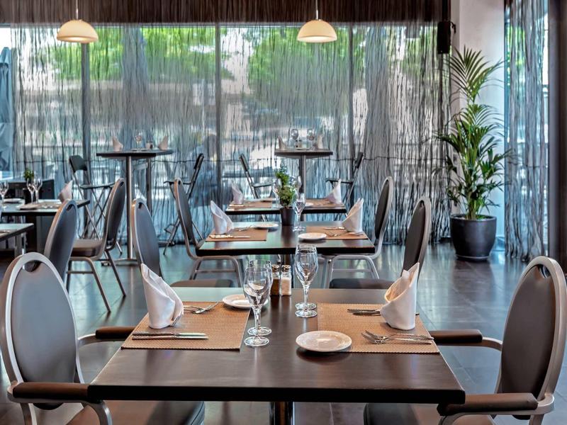 Restaurante moderno con mesas elegantes, sillas grises y decoración con plantas y luz natural