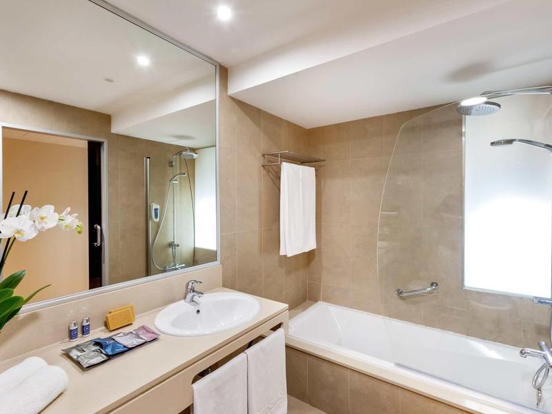 Baño luminoso con bañera, espejo y lavabo moderno en tonos cálidos.