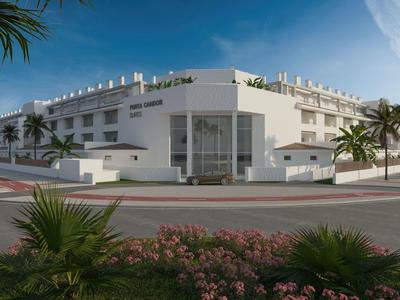 Modernes weißes Hotelgebäude mit Palmen an einer Kreuzung bei klarem Himmel.