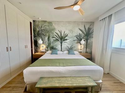 Gemütliches Schlafzimmer mit Doppelbett, grünem Wandbild und Deckenventilator.