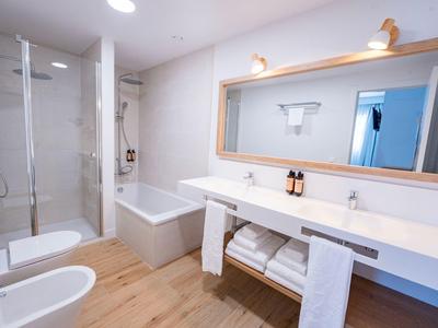 Moderne Badezimmer mit Dusche, Badewanne, Doppelwaschbecken und Holzboden.
